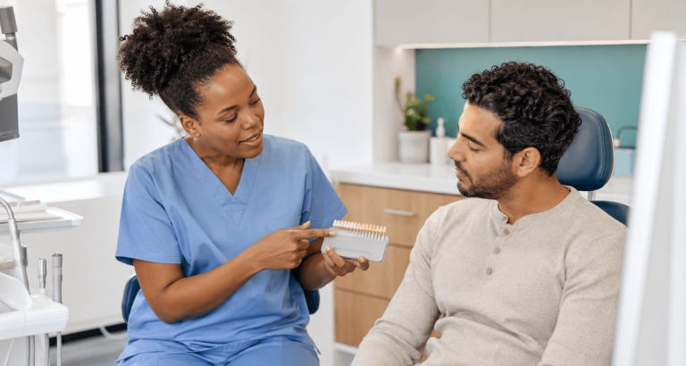 Dentist discussing cosmetic dental options with a patient using a tooth colour guide.